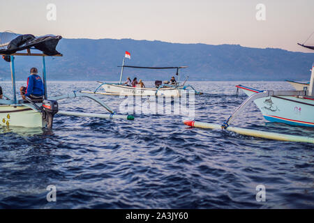 Bali, Indonesia, August 17, 2019: Free dolphins in the sea jump out of the water near the boat Stock Photo