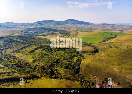 Autumn view. Hilly terrain. Yellow slopes and trees contrast with green fields. Top view of the field in Altai. Stock Photo