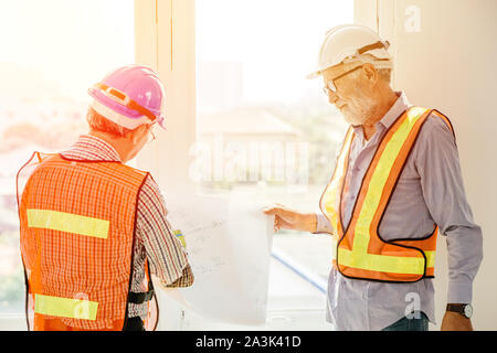 two builder engineer working together consulting about building floor plan in construction site Stock Photo