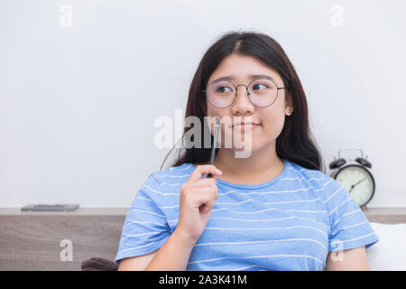 Asian girl teen thinking consider about work plus size nerd wearing glasses people Stock Photo