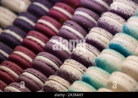 Almond cake macaron with a viscous middle and crispy shell is one of the most fashionable cakes of modern France. Multi-colored macarons lie in rows. Stock Photo