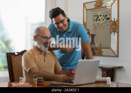 Father and son looking at the laptop while making an online payment. (Family) Stock Photo