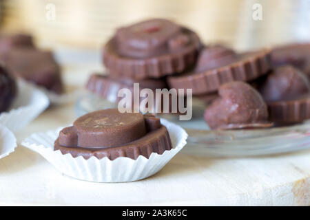 Homemade raw chocolate sweet candies with raspberries inside lay on kitchen desk. Delicious vegan dessert. Raw foods sweeties. Stock Photo