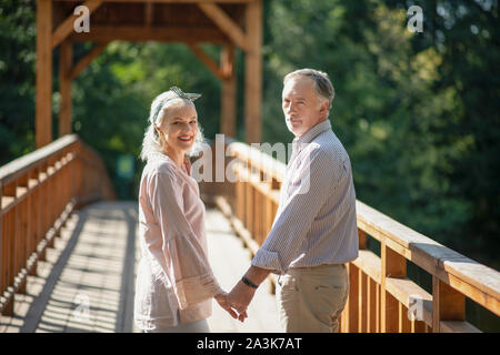 Couple walking hand in hand on the wooden bridge Stock Photo