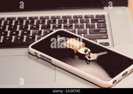 Smartphone and padlock is lying on a laptop keyboard Stock Photo