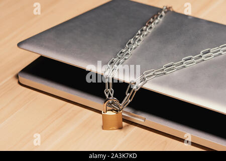 Heavy chain with a padlock around a laptop on table. Stock Photo