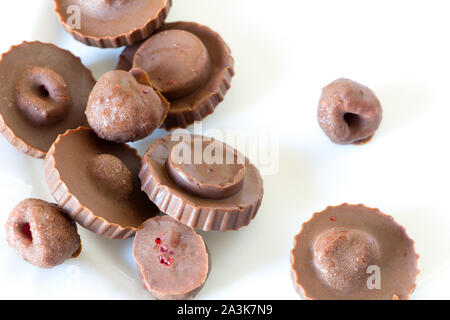 Homemade raw chocolate sweet candies with raspberries inside on white plate. Top view. Delicious candies seem to fly in the air. Stock Photo
