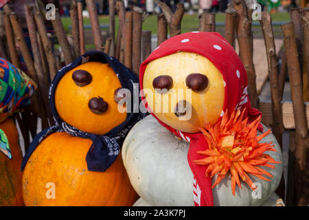 Colorful vegetable couple made from autumn pumpkins and squash with chestnut eyes and bandannas outdoors against a rustic wooden pole fence conceptual Stock Photo