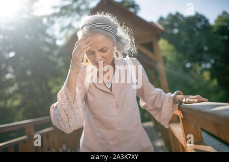 Woman wearing nice earrings having strong headache Stock Photo