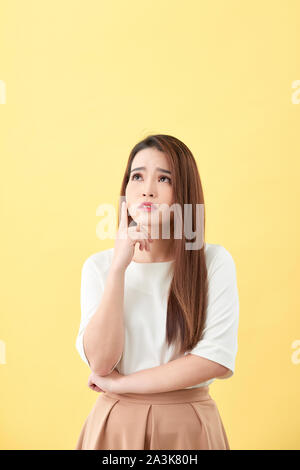 Young business woman thinking making choice, isolated on yellow Stock Photo