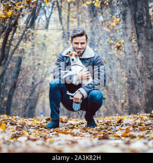Young man walking his dog having a stroll in the autumn park Stock Photo