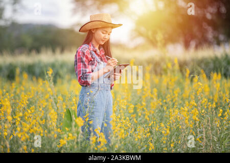 Asian women Agronomist and farmer Using Technology for inspecting in Agricultural and organic vegetable Field Stock Photo