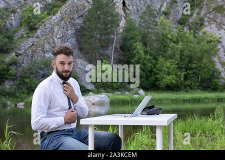 Bearded young man with laptop outdoor. businessman always works, even when on vacation Stock Photo