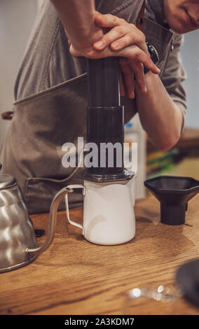 Barista pushing coffee in an aeropress. Alternative method. Stock Photo
