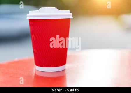 Red paper cup for drinks on a background of nature. Cup coffee or tea from recyclable materials. Free space for text. Mock up. Stock Photo