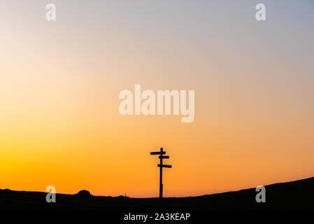 21/8-19, Mugarra, Pais vasco, Spain. A lonely  wooden signpost with three signs in different directions silhouetted against a beautiful sunset sky. Stock Photo