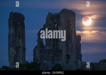 The partially eclipsed moon over Corfe Castle, Dorset, England, UK Stock Photo