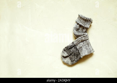Handmade warm knitted sock grey color on textured background with copy space.Winter and autumn concept of eco clothes.Minimalism Kinfolk Style Stock Photo
