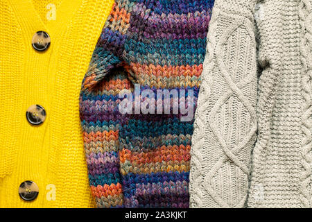 Bunch or pile of stylish cozy knitted color sweaters with different knitting patterns.Texture of woolen things background.Fall winter season knitwear Stock Photo