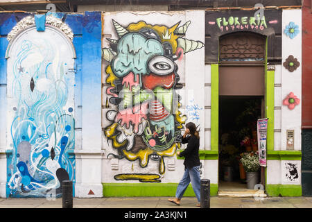 Lima Barranco street art - woman walking past a graffiti decorated wall in the Barranco district of Lima, Peru, South America. Stock Photo