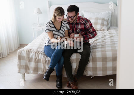 Happy couple using digital tablet in bedroom Stock Photo