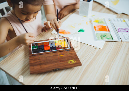 Young Asian beautiful mom with her daughter kid painting at home. Stock Photo