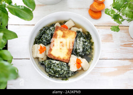 Vegetable consomme with dumplings, fried tofu and seaweed.  Appetizing vegetarian soup. Stock Photo