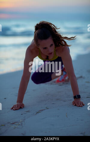 active sports woman in sport style clothes on the seacoast in the evening training. Stock Photo