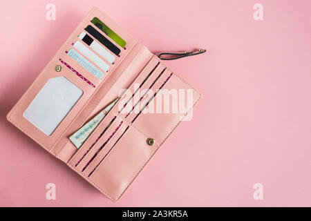 Open female pink wallet. Flat lay. Copy space. Contents in the fashion purse. Stock Photo