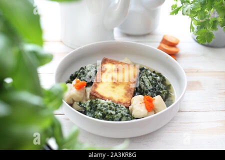 Vegetable consomme with dumplings, fried tofu and seaweed.   Appetizing French style vegetarian soup. Stock Photo