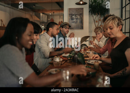 Diverse friends talking over a bistro dinner at night Stock Photo