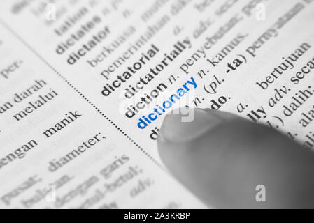 close up of a finger pointing to DICTIONARY word in english to 