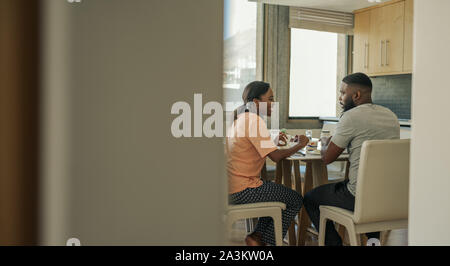 Smiling young African American couple talking together over breakfast Stock Photo