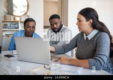 Financial planner talking with an African American couple at home Stock Photo