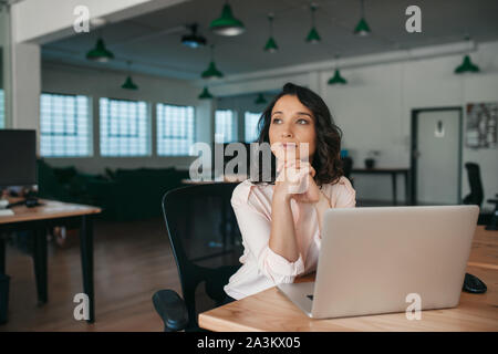 Young businesswoman thinking about work while sitting at her desk Stock Photo