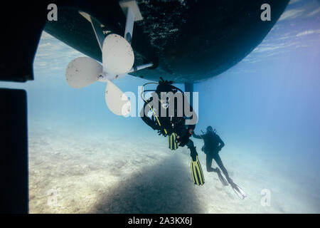 Two technical divers repairing ship propeller underwater. Technical diving. Scuba divers under ship keel Stock Photo