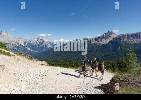 climbers walking down a road in a Dolomite mountain landscape after a hard climb with a great panorama view behind them of the Alta Badia mountains Stock Photo