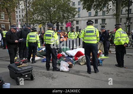 Police form a cordon arround protesters who have glued themselves to each other in a circle, adjacent to the Women of World War Two memorial on Whitehall, during the third day of an Extinction Rebellion (XR) protest in Westminster, London. Stock Photo