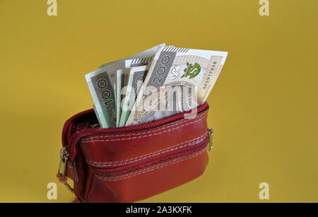 Red leather wallet / purse opwn with banknotes of 200 Polish zloty inside isolated on yellow background close up. Stock Photo