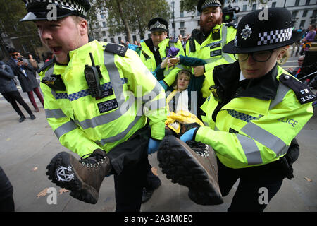 Police arrest a protester who had been glued to to others in a circle, adjacent to the Women of World War Two memorial on Whitehall, during the third day of an Extinction Rebellion (XR) protest in Westminster, London. Stock Photo