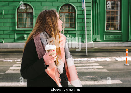 Sad young woman in warm clothing standing in city street in winter Stock Photo
