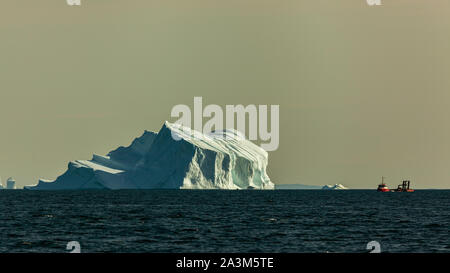 A red fishing boat near icebergs in Disco Bay (Greenland)  during summer Stock Photo