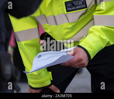 Whitehall, London, UK. 9th October 2019. Large police presence makes arrests and removes Extinction Rebellion activists who have glued themselves to Whitehall. Officer reads a Section 14 Public Order Act notice to two demonstrators on the road. Credit: Malcolm Park/Alamy Live News.