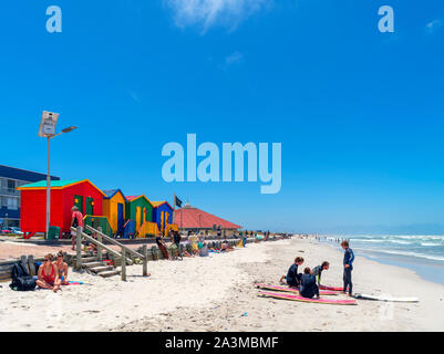 Surfers in front of colourful Victorian beach huts in Muizenberg, Cape Town, Western Cape, South Africa Stock Photo