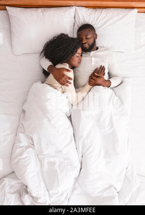 Black family couple lying and cuddling in bed, sleeping together. Stock Photo