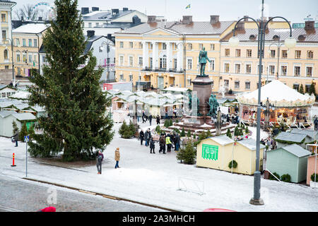 Helsinki, Finland, 19.12.2018: Christmas Market With Christmas Tree On Senate Square covered with snow. Holiday Carousel And people walking. Stock Photo