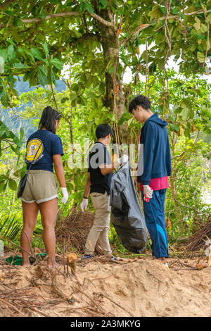 People of different nationalities cleaning garbage on the black beach to clean the beach in the world environment, volunteer concept Stock Photo