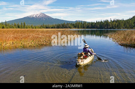 Kayakers on Hosmer Lake in the Oregon Cascade Mountains in early autumn. Mount Bachelor is in the background. Stock Photo