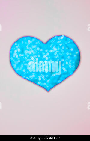 Blue blurred shiny heart on beige background, abstract Stock Photo