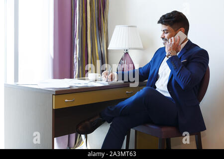 Eastern man in suit working in hotel, talking by phone Stock Photo